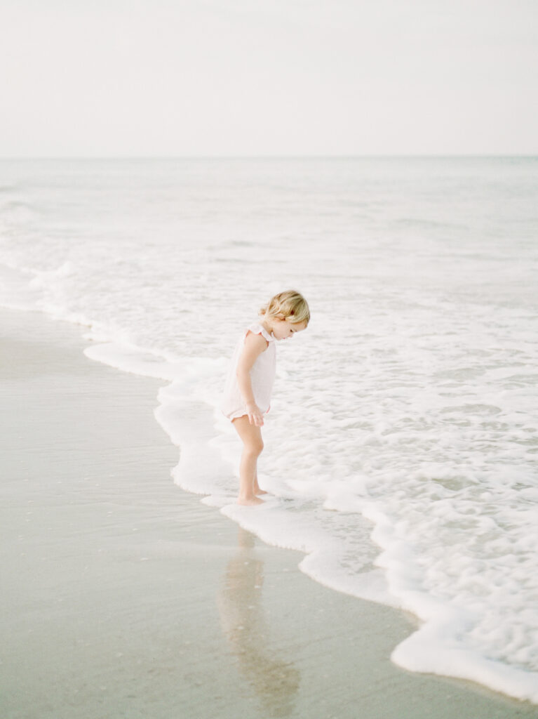 little girl staring at her feet in the ocean by Orlando Lifestyle photographer