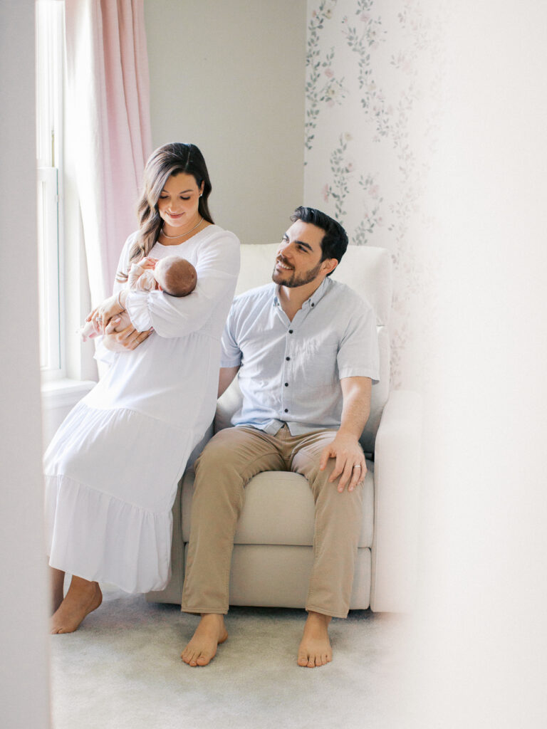 New baby girl in her sweet nursery with parents by Orlando newborn photographer.