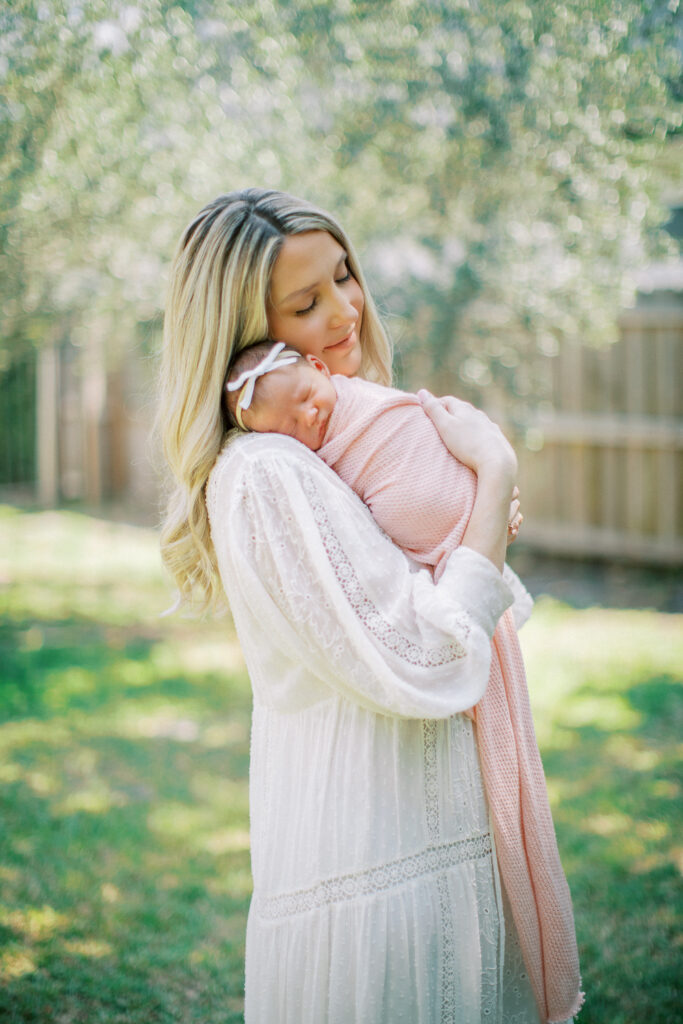 mother gently cradling newborn during family-centered photo session