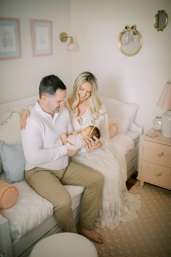 Parents sit in nursery cuddling newborn baby during in-home Orlando session, showing intimate family connection