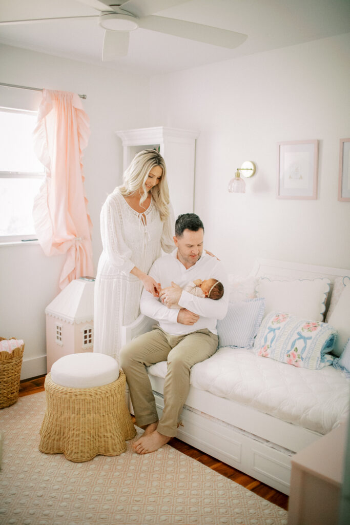 Emotional moment as mother admires father gently cradling newborn during family-centered photo session in the baby's nursery