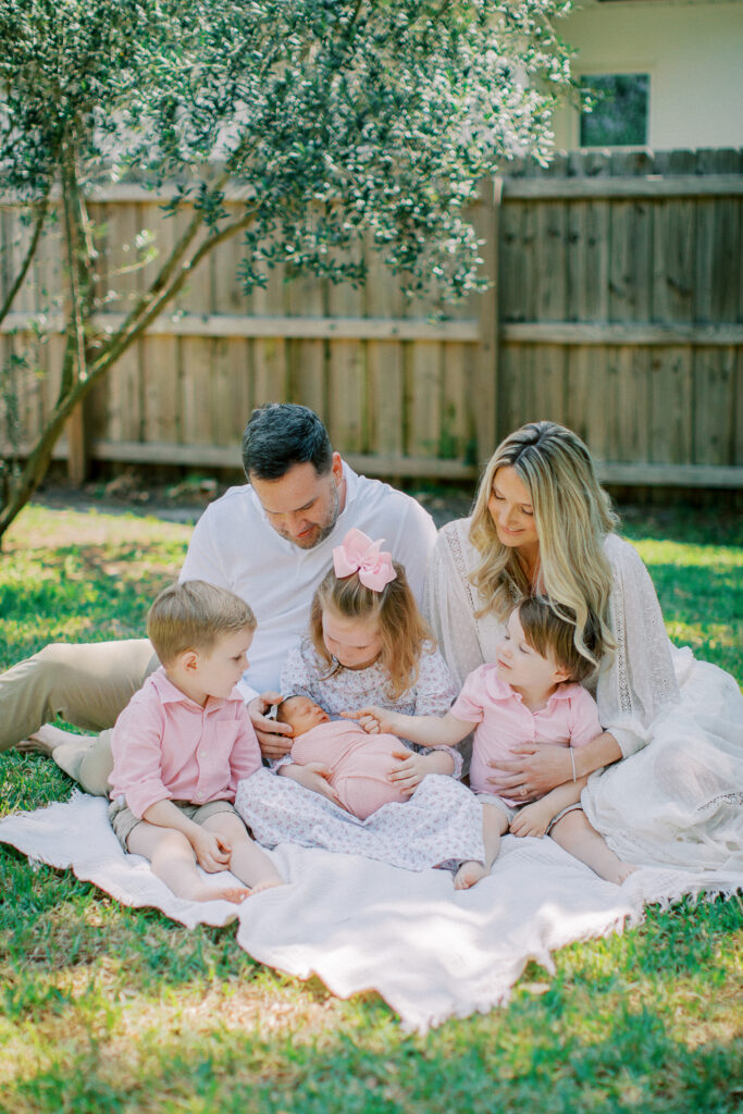 Children holding newborn sibling in relaxed family portrait session in Winter Park, FL