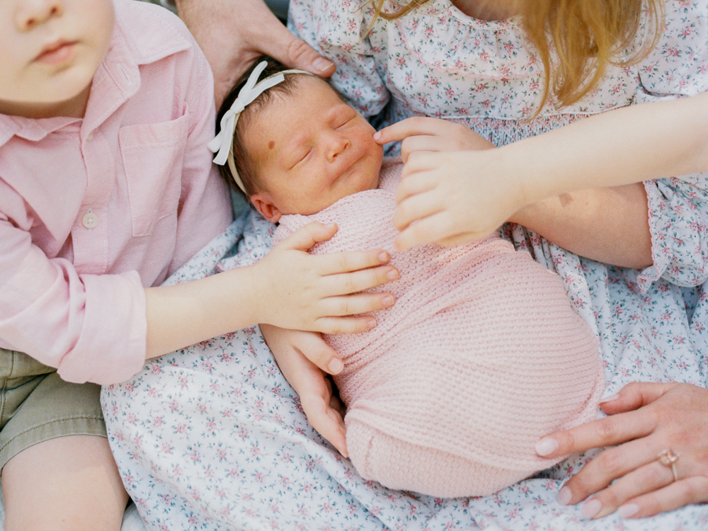 Toddler meeting newborn sibling in relaxed family portrait session in Winter Park, FL