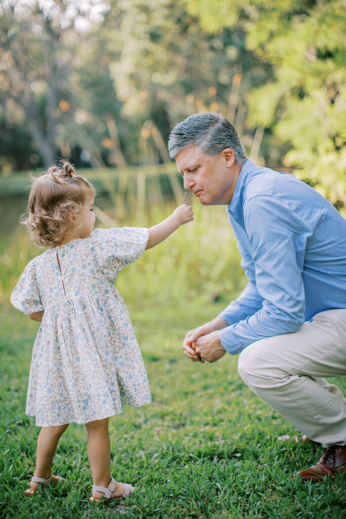 Toddler showing a flower for dad to smell at a morning photo session by Orlando family photographer.