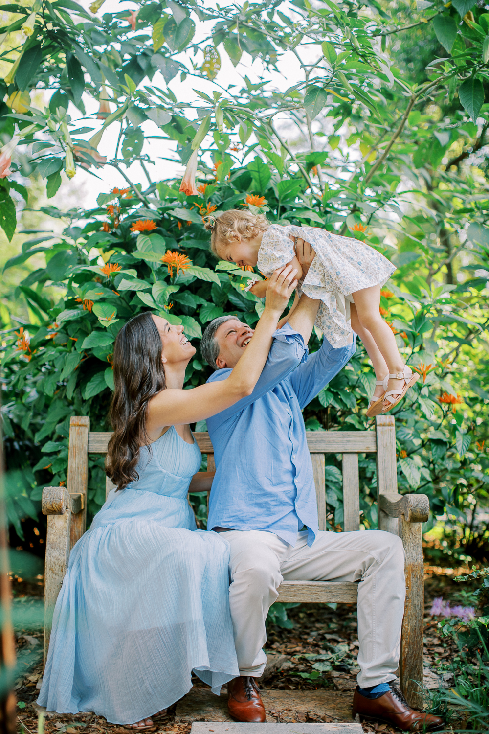 Father lifting toddler into the air in the garden.