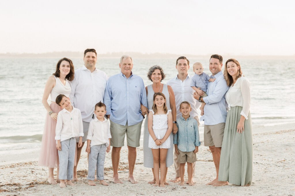 Soft colors and golden sand create a warm, relaxed atmosphere for this multigenerational family portrait.