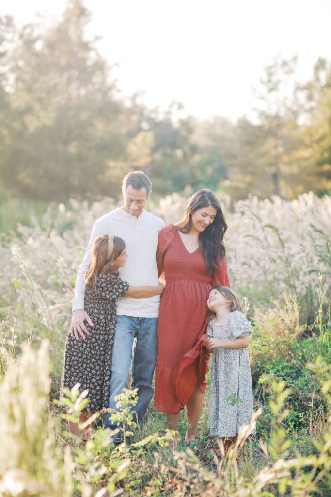 A family walking through a field together at sunset. by Orlando family photographer. 