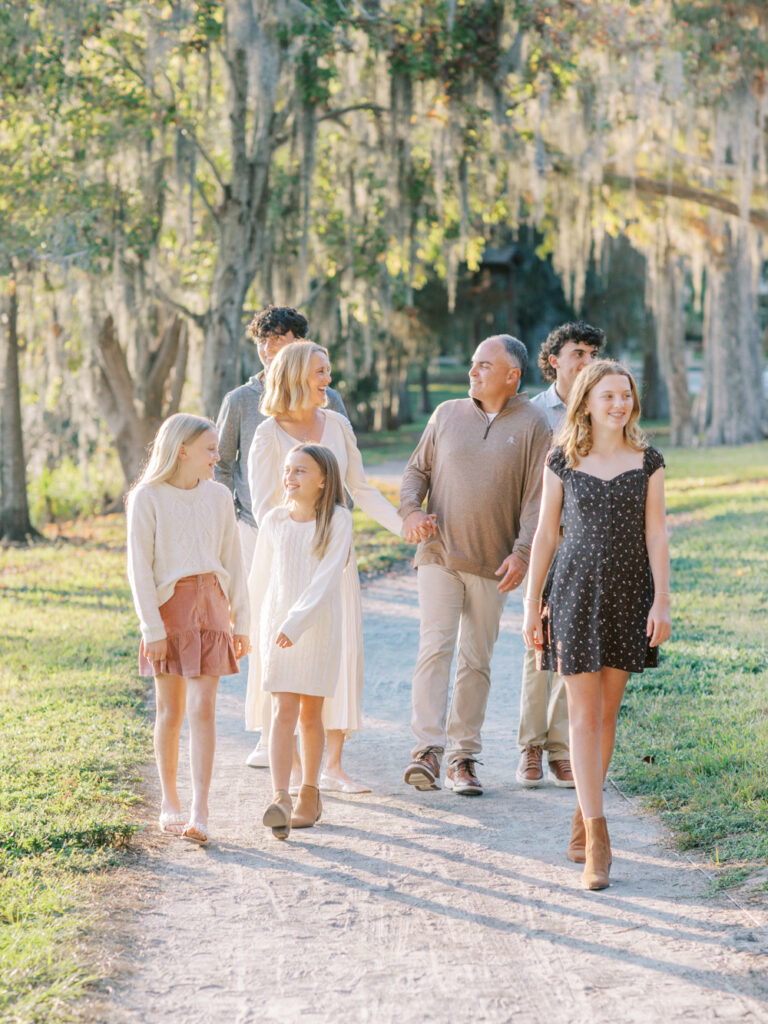 Family walking together on light filled pathway by Orlando family photographer.