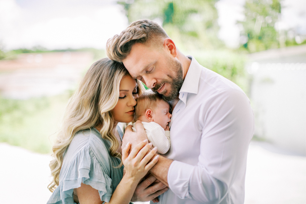 Mom and dad with baby at home in a natural backyard setting. 