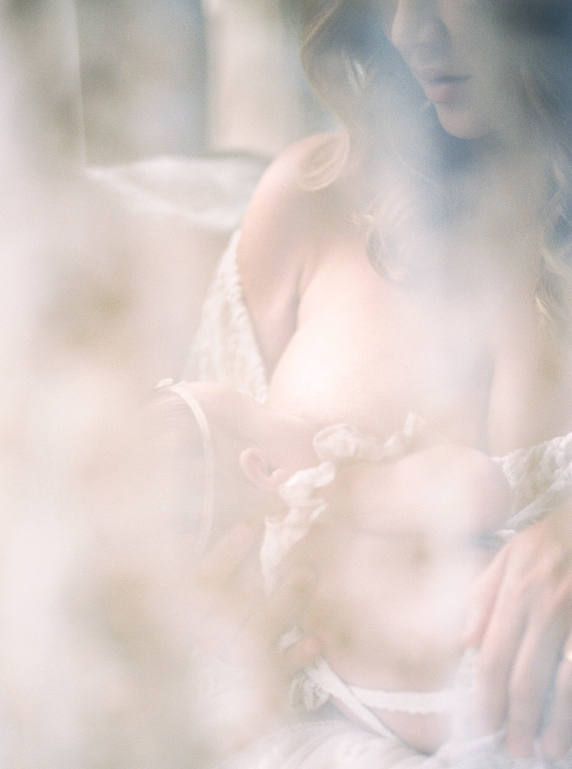 Mother nursing baby creative light filled photograph.