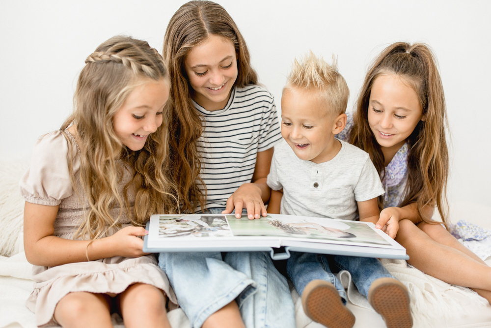 Children looking at an heirloom album by Orlando newborn photographer. 