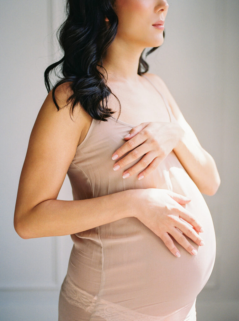 Details of a stunning mother expecting a new baby in sublime window light.