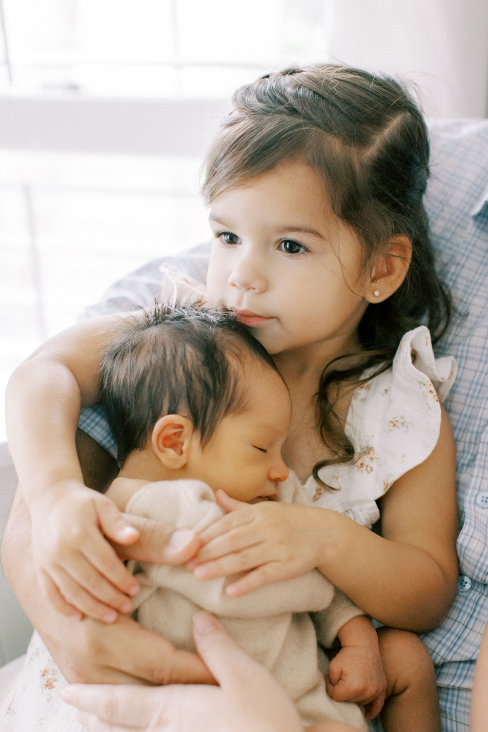 Big sister snuggling her new baby brother by Orlando in-home photographer.